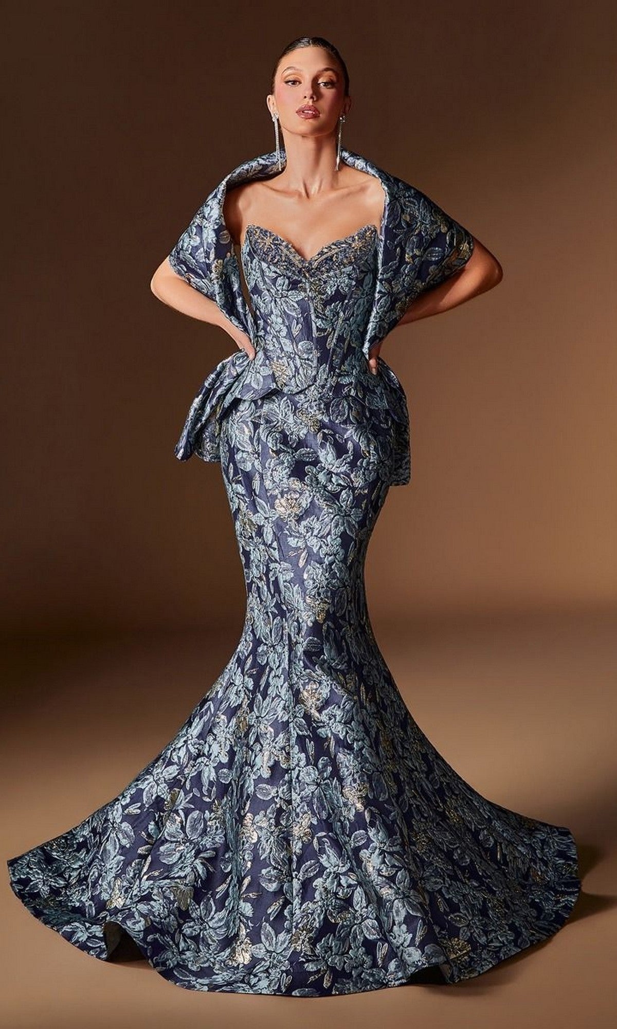A woman poses against a plain brown background wearing the Ladivine CD655, a navy long formal dress featuring a fitted, floor-length floral jacquard design with an elegant corset bodice, dramatic flared hem, and matching shawl.